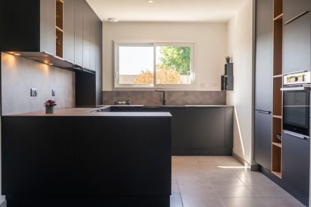 Cuisine moderne noire et bois en angle à Bordeaux, agencement sur mesure au design contemporain alliant contraste des matières et élégance